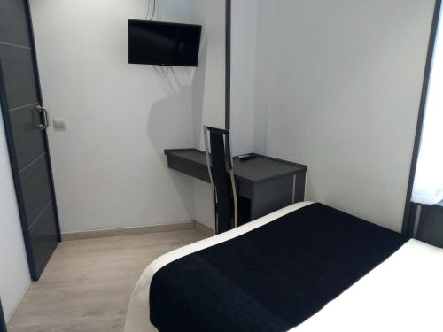 a small room with a bed and a television at Hostal Doña Isabel in Majadahonda