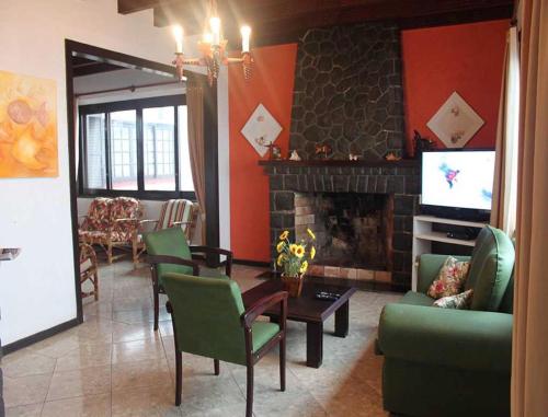 a living room with green chairs and a fireplace at Pousada Solar Inn in Torres