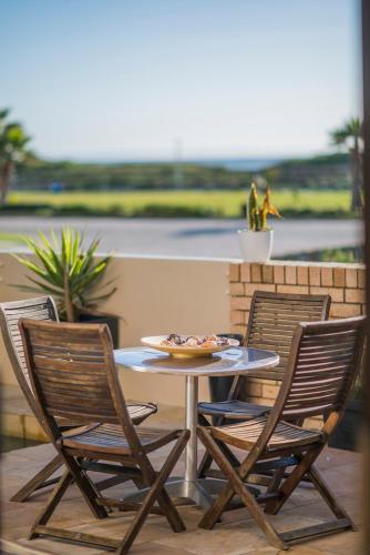 a table and two chairs with a plate of food on it at Palm Beach Guesthouse in Port Elizabeth