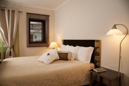a bedroom with a bed and a lamp and a window at Vila dos Castanheiros in Ferreira do Zêzere