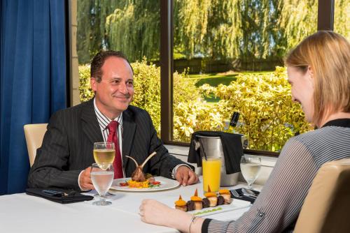 a man and woman sitting at a table with a plate of food at Distinction Hamilton Hotel & Conference Centre in Hamilton
