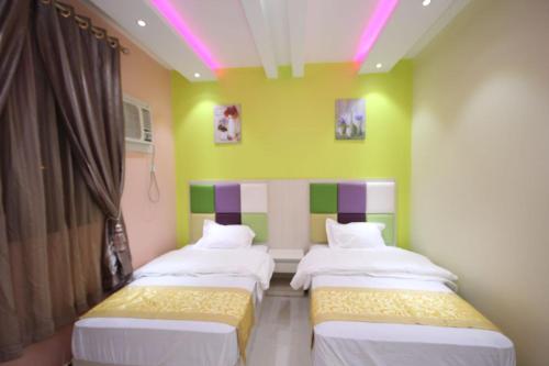 2 Betten in einem Zimmer mit Grün und Lila in der Unterkunft Nakhil Moon Serviced Apartments in Wadi ad-Dawasir