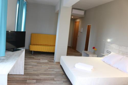 a bedroom with a white bed and a yellow couch at Te Maná Hotel in Torreblanca