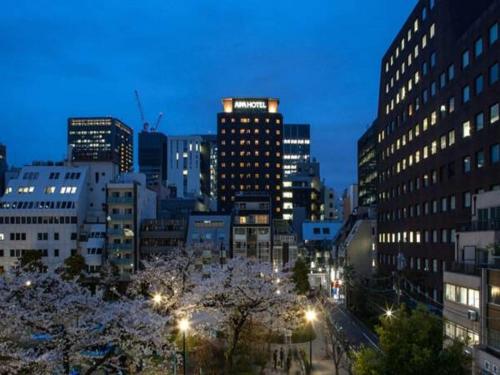 東京にあるアパホテル〈新橋 虎ノ門〉の夜の建物や街灯が見える街並み