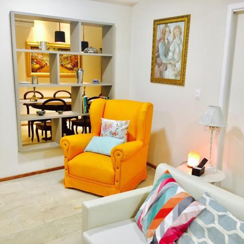 an orange chair in a living room with a table at Hospedaria Conceitual in Florianópolis