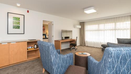 a living room with two blue chairs and a table at Distinction Hamilton Hotel & Conference Centre in Hamilton