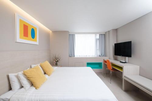 1 dormitorio blanco con 1 cama y TV en New Seoul Hotel Myeongdong, en Seúl