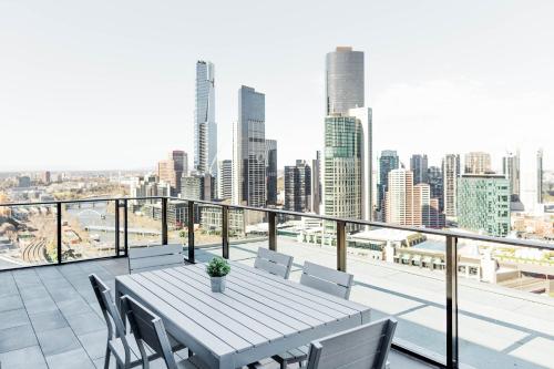 a table and chairs on a balcony with a view of a city at The Canvas Apartment Hotel in Melbourne