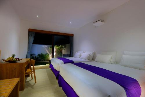 a bedroom with a large bed and a desk and a window at Anema Wellness & Resort Gili Lombok - Diving Center PADI in Tanjung