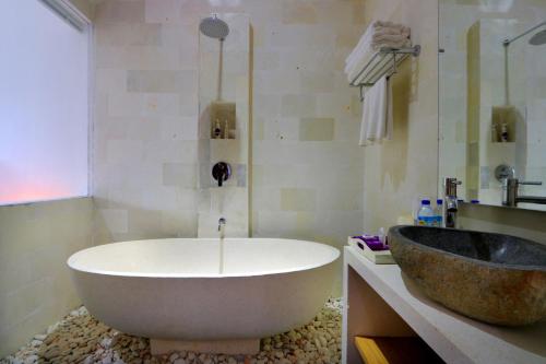 a bathroom with a large tub and a sink at Anema Wellness & Resort Gili Lombok - Diving Center PADI in Tanjung
