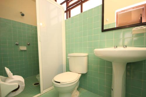 a green tiled bathroom with a toilet and a sink at Hotel San Martin in San Cristóbal de Las Casas