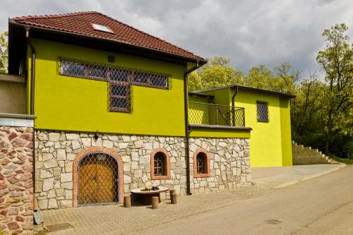 um edifício amarelo com um banco à frente em Penzion - Vinařství Hanuš em Blučina