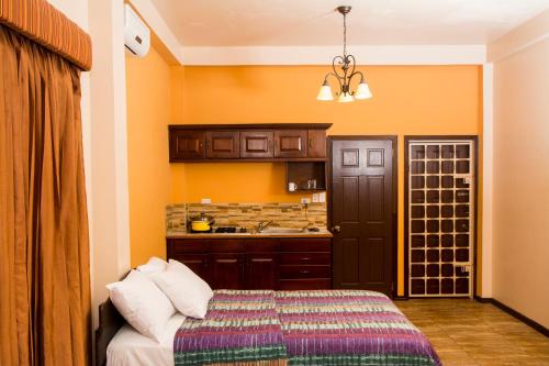 um quarto com uma cama e uma cozinha com paredes cor de laranja em Windjammer International Cuisine & Comfort Inn em Georgetown