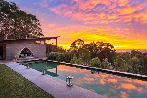 a pool in front of a house with a sunset at Spicers Sangoma Retreat - Adults Only in Kurrajong