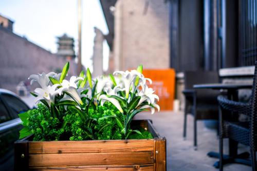 a wooden planter with white flowers on a sidewalk at Elsewhere Hotel Inn North Street Branch in Pingyao