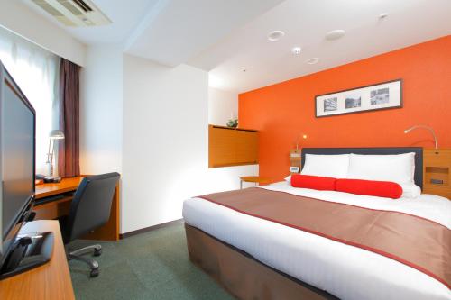a hotel room with a bed with an orange wall at HOTEL MYSTAYS Kamata in Tokyo