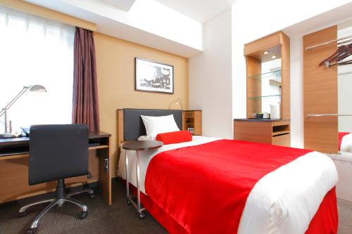 a bedroom with a bed with a desk and a red blanket at HOTEL MYSTAYS Kamata in Tokyo