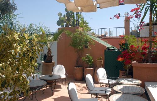 a patio with chairs and tables and potted plants at Riad Celia in Marrakech