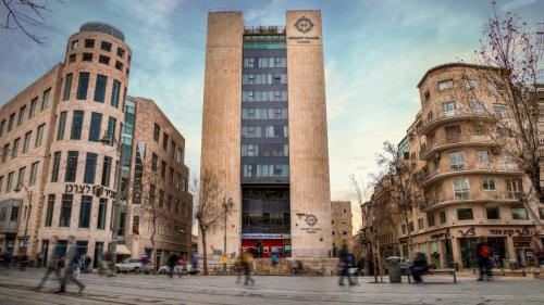 two tall buildings with people walking in a city at Herbert Samuel Jerusalem in Jerusalem