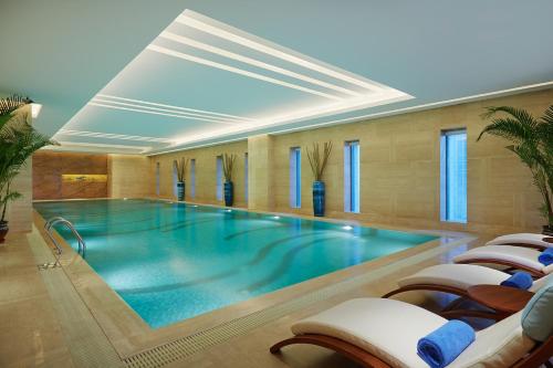 a swimming pool in a hotel with chairs around it at Wanda Realm Huaian in Huai'an