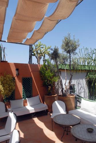 a patio with white chairs and tables and an umbrella at Riad Celia in Marrakech