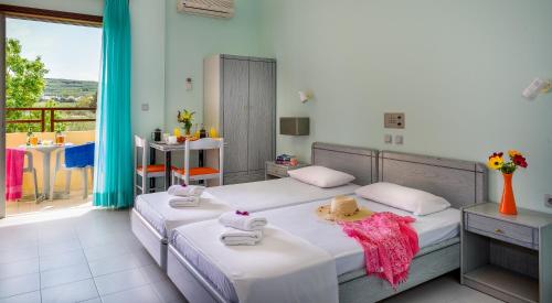 a bedroom with two beds and a balcony at Louladakis Apartments in Kolymvari