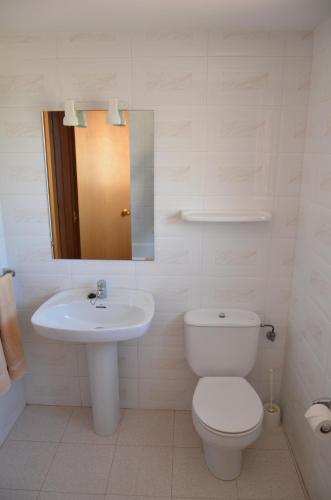 a white bathroom with a toilet and a sink at Apartamentos Oasis Benidorm in Benidorm