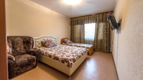 a bedroom with a chair and a bed and a window at Apartments at Michurina 15 in Kemerovo