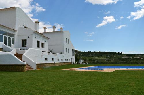 a white house with a swimming pool in front of it at Hotel Rural Ibipozo in El Almicerán