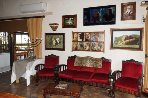 a living room with red chairs and a table at Cheetau Lodge in Ebenhaezer