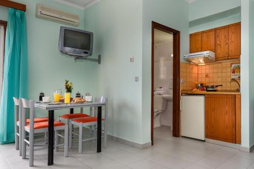 a kitchen with a table with chairs and a television on the wall at Louladakis Apartments in Kolymvari