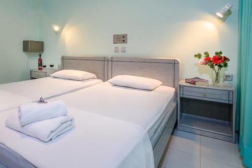 a bedroom with two beds and a vase of flowers at Louladakis Apartments in Kolymvari