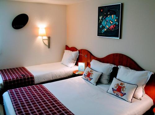 a hotel room with two beds in a room at Greenhotels Roissy Parc des Expositions in Tremblay En France