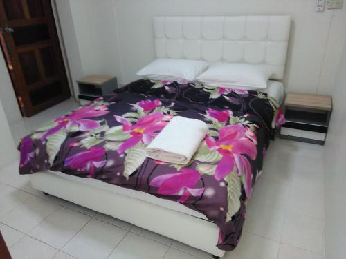 a bedroom with a bed with a floral bedspread at NB House in Karon Beach