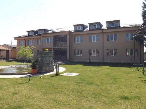 a large building with a grass yard in front of it at Casa Dobrescu Centura De Nord in Craiova
