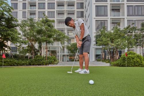 a man is playing golf on a putting green at 137 Pillars Residences Bangkok in Bangkok