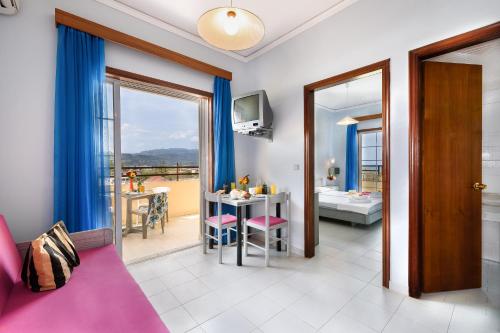 a living room with a pink couch and a room with a table at Louladakis Apartments in Kolymvari