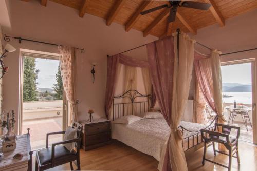 a bedroom with a canopy bed and a balcony at Villa Maira Luxurious with private swimming pool in Korfos