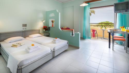 a bedroom with two beds and a table and a balcony at Louladakis Apartments in Kolymvari