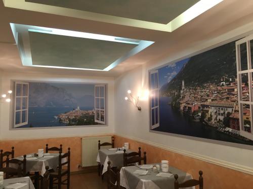 a dining room with two tables and two large windows at Hotel Vela Azzurra in Malcesine