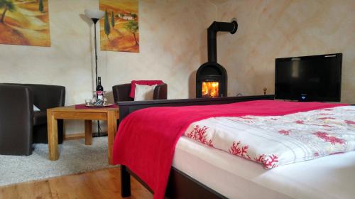 a bedroom with a fireplace and a bed with a red blanket at Maifeld-Fewo Rhapsodie in Kerben