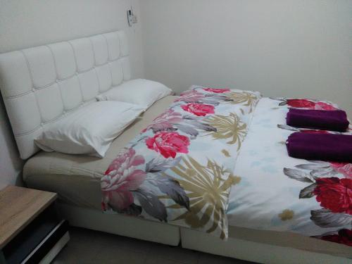 a bed with a white headboard with flowers on it at NB House in Karon Beach