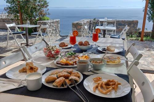 a table with plates of food on it with the ocean at Aegila Boutique Hotel in Éxo Nímfion