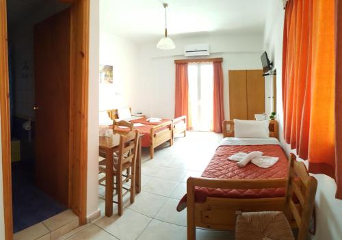 a room with two beds and a dining room with a table at Sofia Studios & Apartments in Georgioupolis