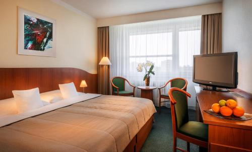 a hotel room with a bed and a table with a television at Clarion Congress Hotel Ostrava in Ostrava