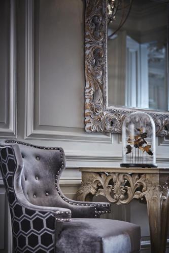 a chair next to a table with a mirror at Barnett Hill Hotel in Guildford