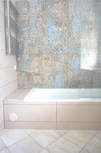 a bath tub in a bathroom with a tile wall at Palmeira VIP Apartment in Portimão