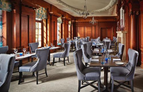 a restaurant with wooden walls and tables and chairs at Barnett Hill Hotel in Guildford