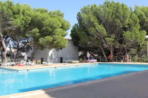 una piscina en un complejo con árboles en el fondo en Apartamentos Sol Isla en Arenal d'en Castell