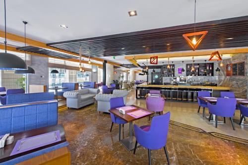 a restaurant with purple chairs and a bar at Somewhere Hotel Apartment in Dubai